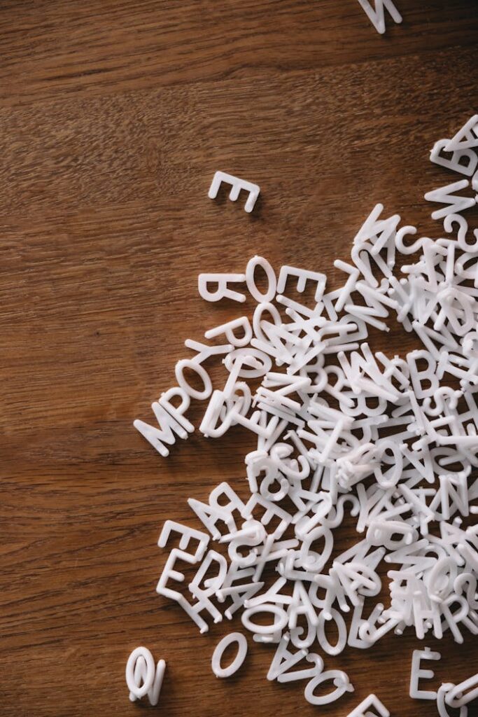 A close-up of white plastic letters scattered on a brown wooden background, perfect for design concepts.